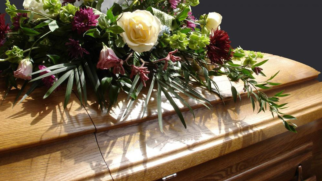 a coffin/casket with flowers on top